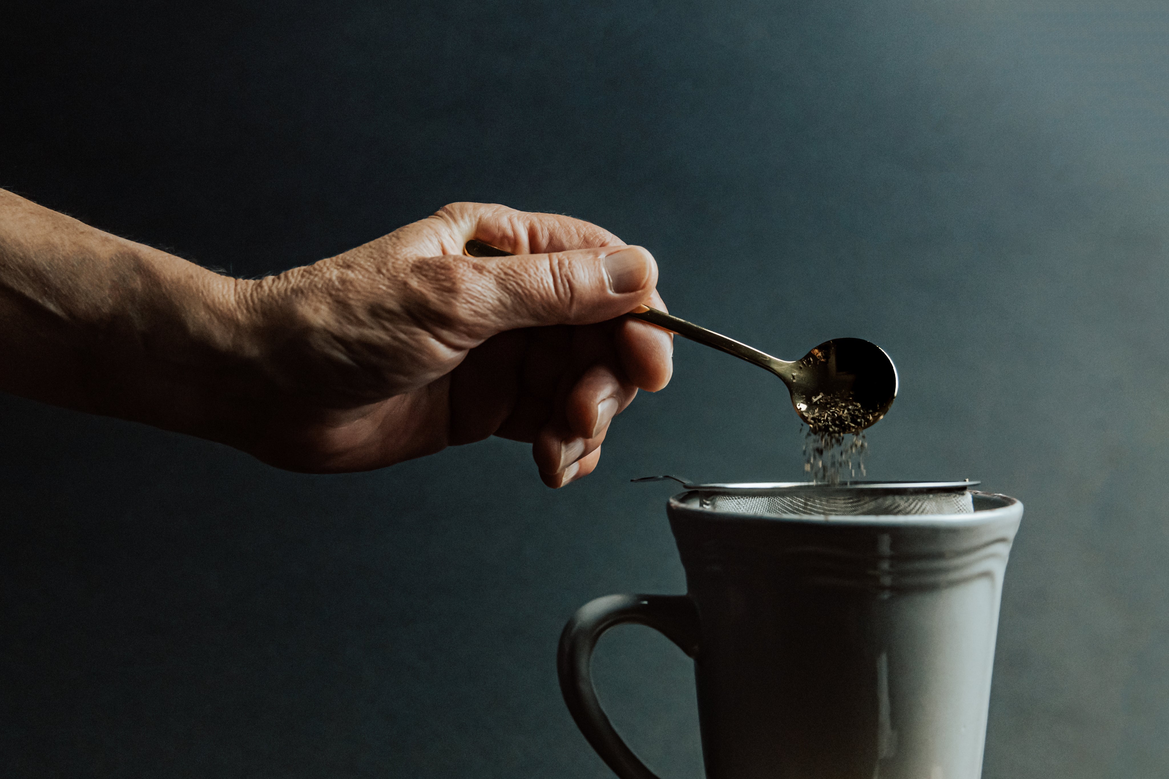 hand-holds-a-spoon-and-adds-loose-leaf-tea-to-a-mug.jpg